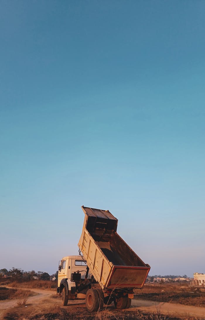 The Art of Drawing Readers In: Your attractive post title goes here A dump truck unloading on a country dirt road in rural India, under a clear blue sky.